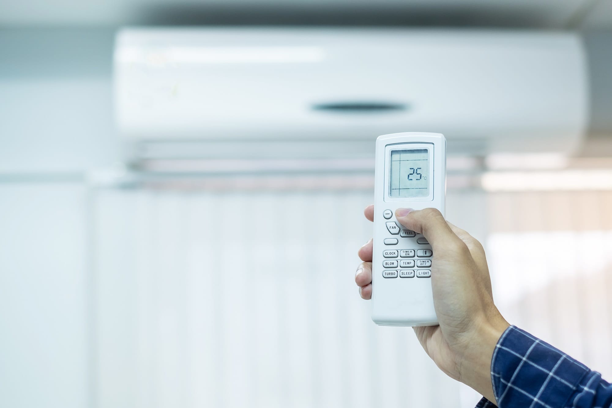 hand using remote controller for adjust Air conditioner